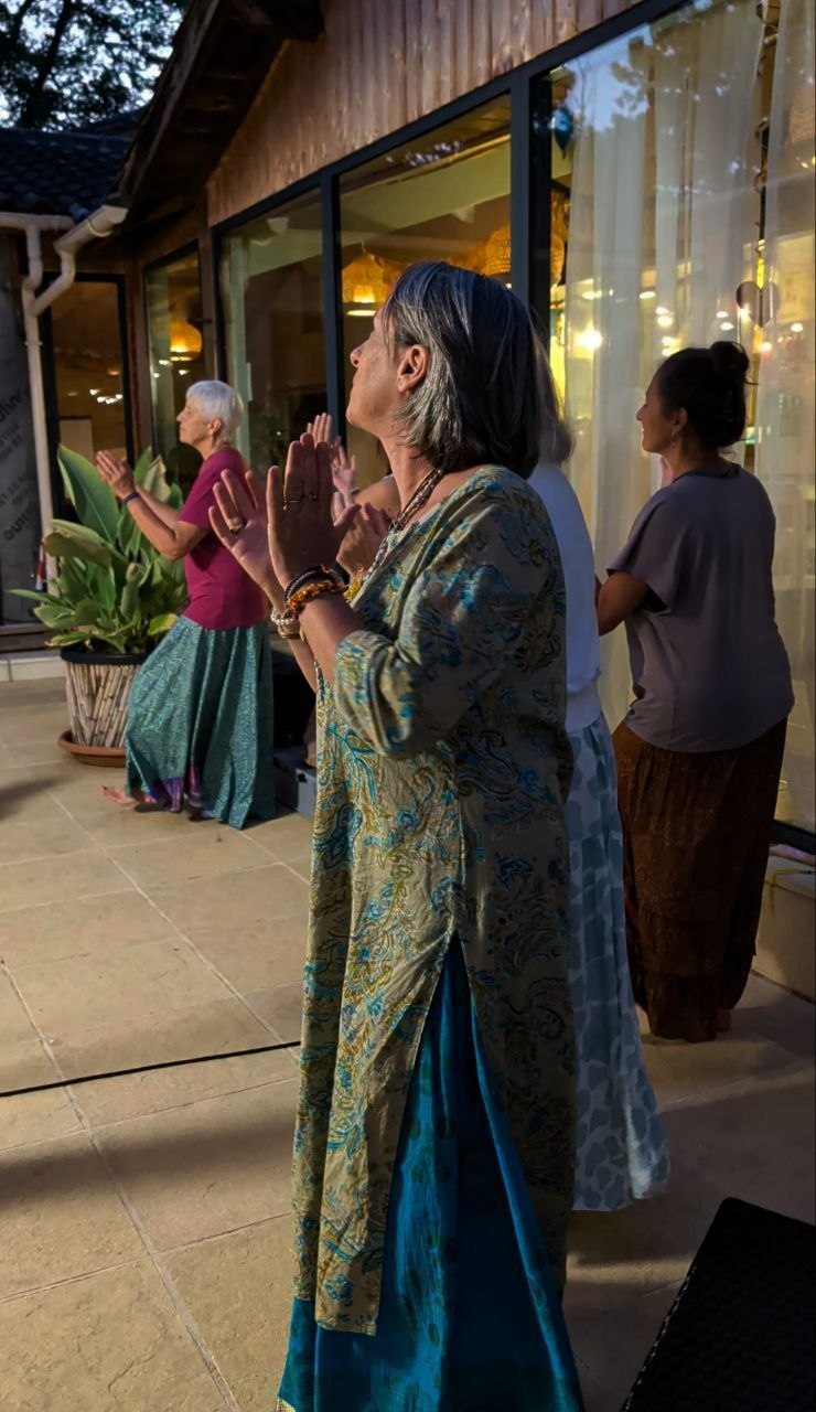 Des participants chantent et frappent dans leurs mains pendant le kirtan, à la tombée du soir